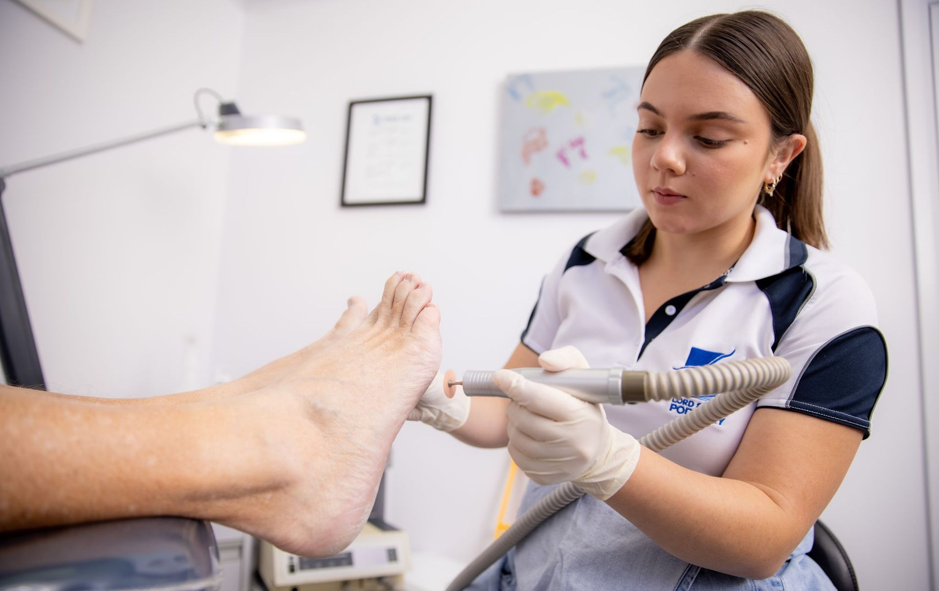 Podiatrist Examining a Patient’s Foot in a Bright Clinic, Wearing Gloves and Holding a Medical Tool — Lord Street Podiatry in Port Macquarie, NSW