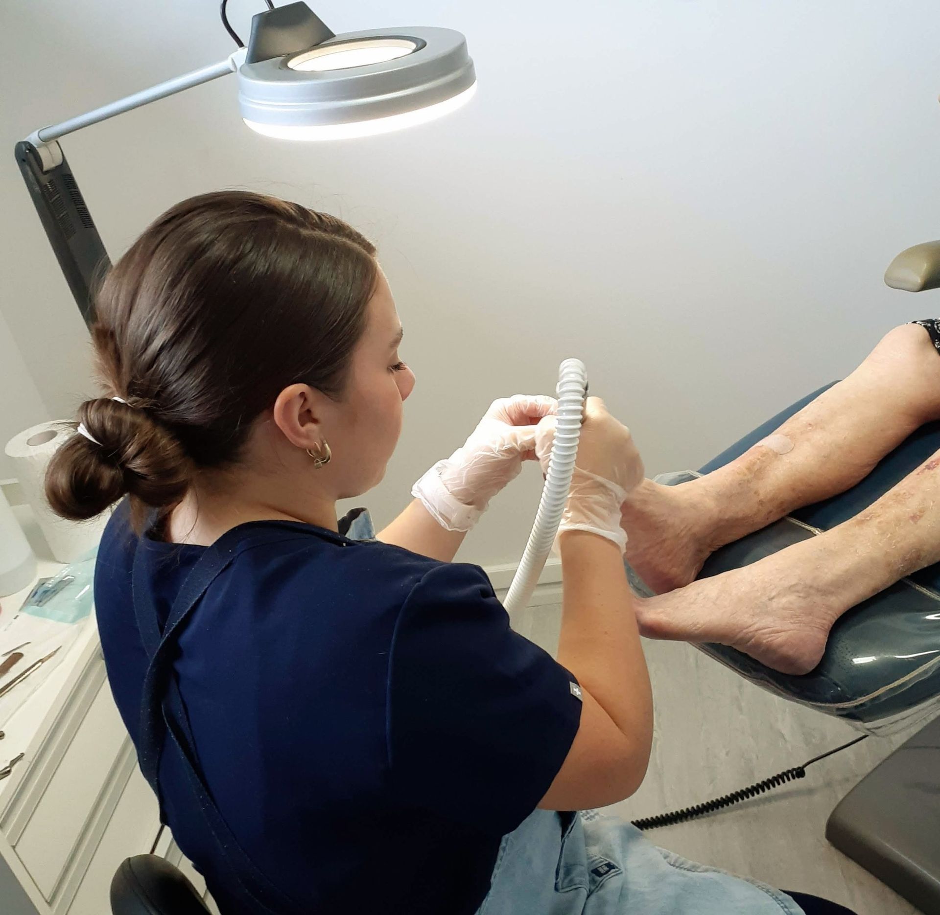 Medical Professional Examining a Patient’s Feet Under a Bright Exam Lamp — Lord Street Podiatry in Port Macquarie, NSW