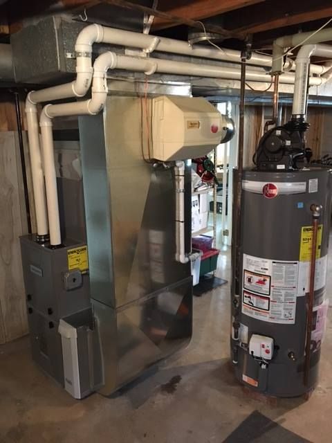 Furnace and water heater in a basement. Ductwork and white PVC pipes are visible.