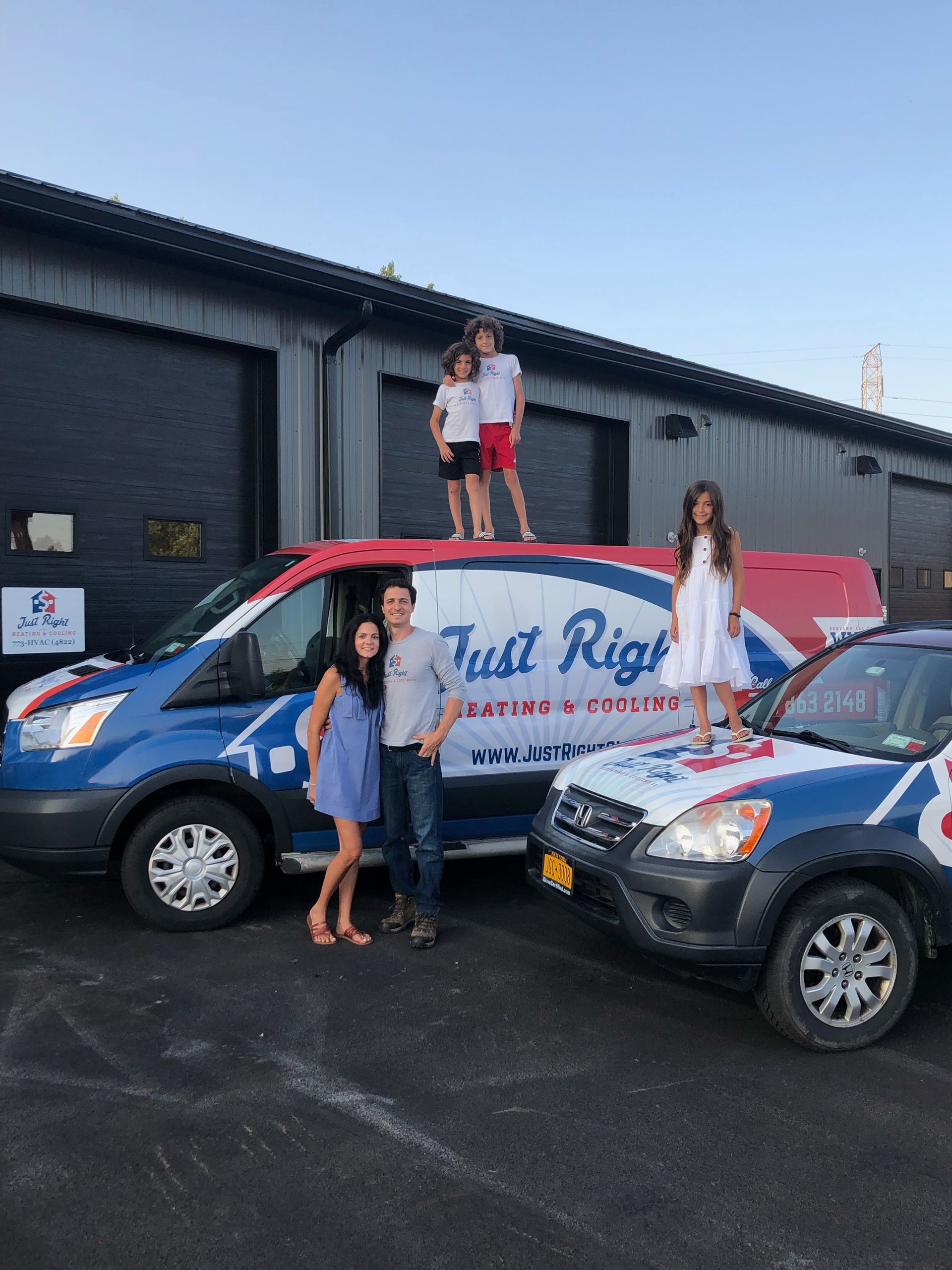 Family posing with Just Right Heating & Cooling vans; children atop van.