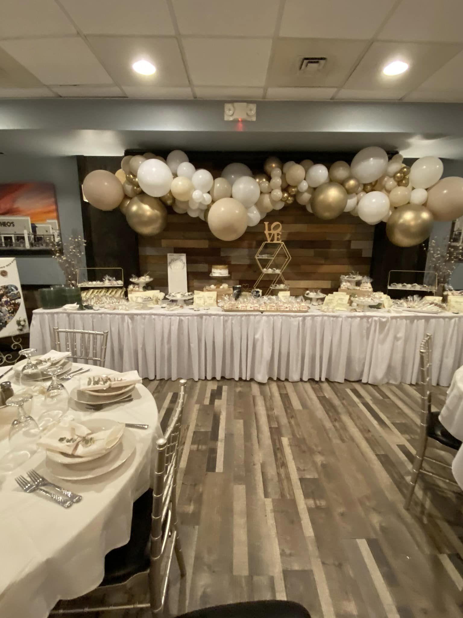 12' organic balloon garland in neutral whites, beiges, and gold accents with natural wood details, styled with a pallet wall backdrop for a sweets table in Highland, IN.