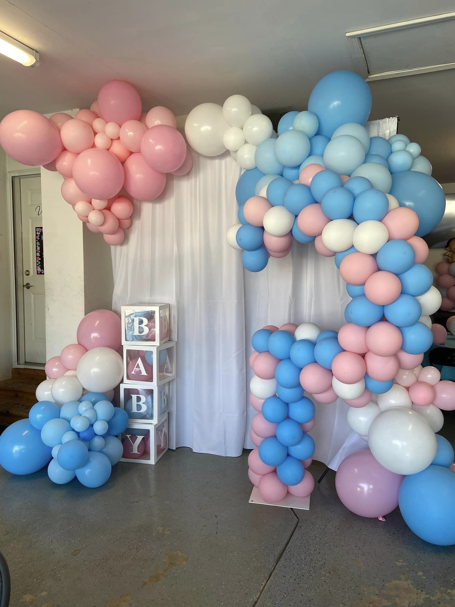 Indoor balloon decor for a gender reveal in Schererville, Indiana, featuring pink and blue balloon garlands, balloon poofs, and a 'Boy or Girl' theme, perfect for family celebrations.