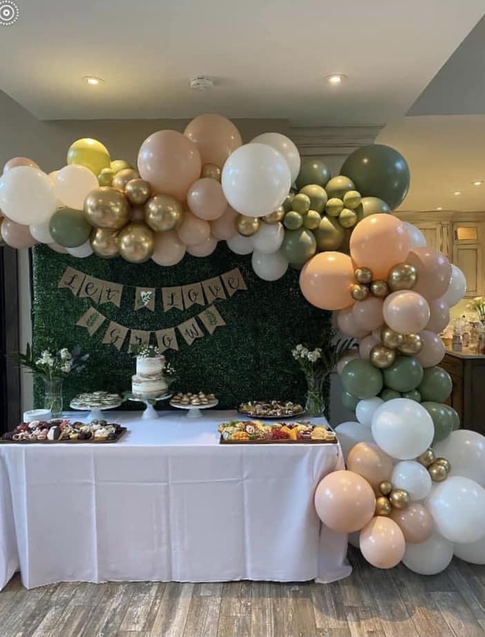 Boho-inspired organic balloon garland with blush, eucalyptus, and gold accents, styled with a sweets table and hedge wall backdrop for an elegant event in Crown Point, Indiana. Perfect for creating a stunning and cohesive celebration setup.
