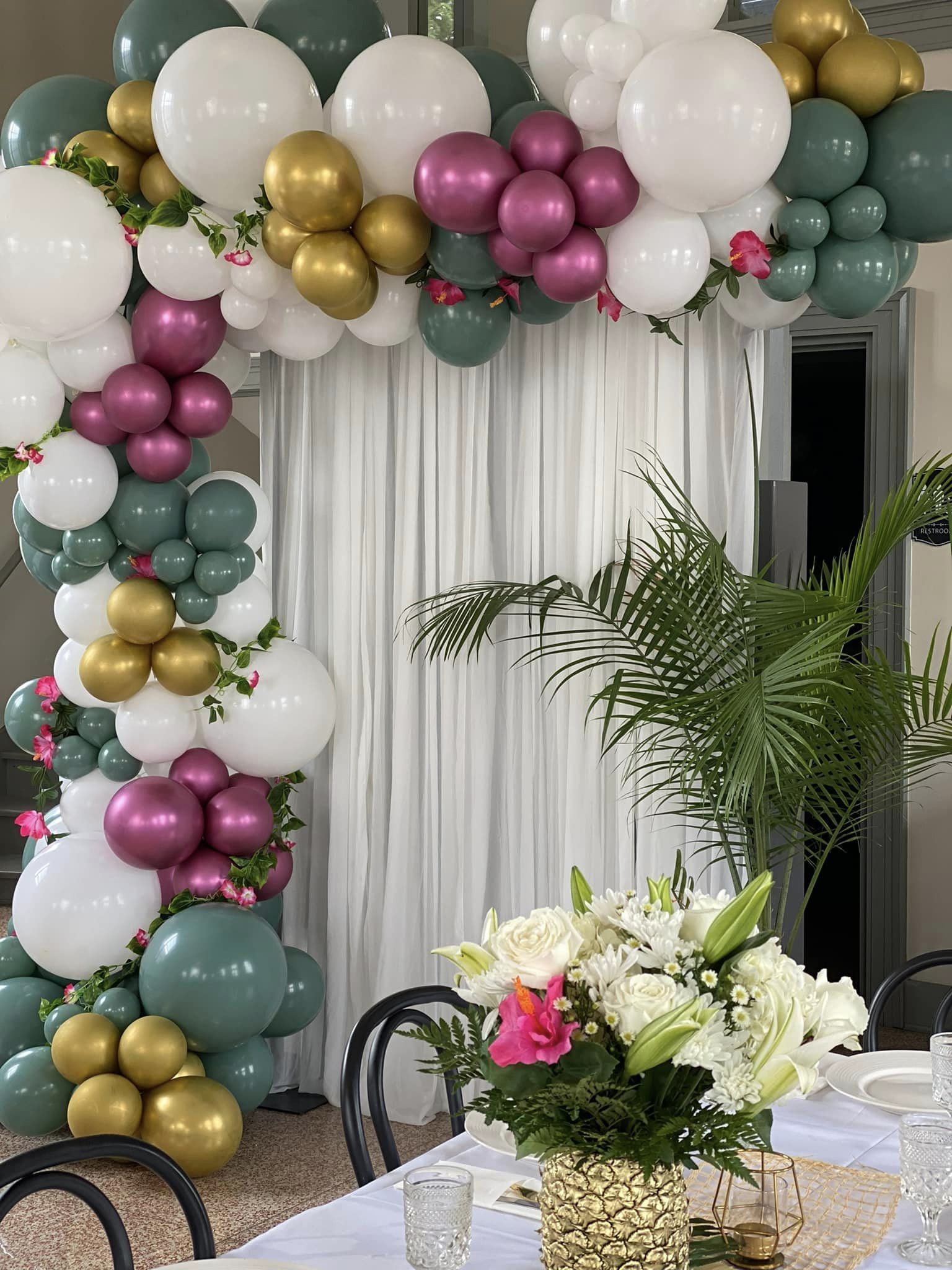 50th Wedding Anniversary backdrop for the head table at a Chicago, IL venue, featuring an organic balloon design in white, sage, and chrome purple with floral accents, creating memories to last a lifetime.