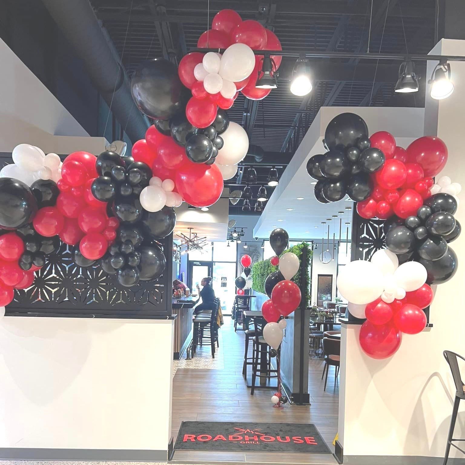 Roadhouse Grill in Demotte, Indiana, featuring ceiling deluxe organic balloon garlands in company colors of red, black, and white. Fun and unique decor that brings excitement throughout the entire establishment, creating a vibrant and welcoming atmosphere for guests.