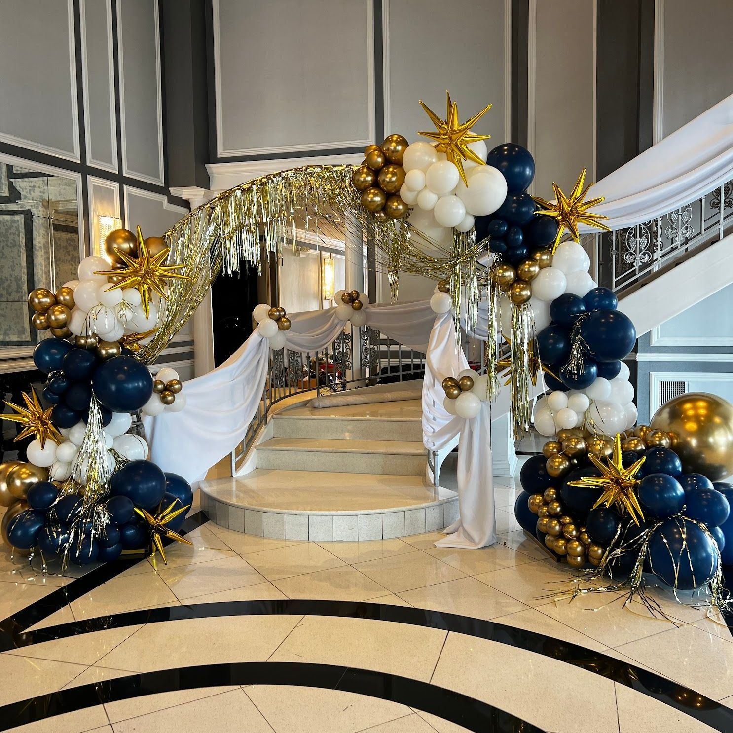 Demi Arch over a staircase with lux garland, starburst and shimmer curtain accents 