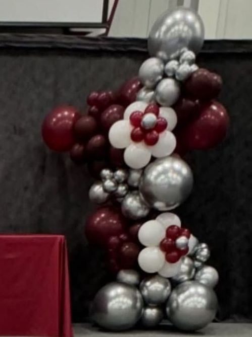 Grand deluxe flower-themed organic balloon column in Forest Ridge Academy's school colors: dark red, white, and pops of chrome silver. Perfect as stage decor for their preschool graduation ceremony in Schererville, IN.