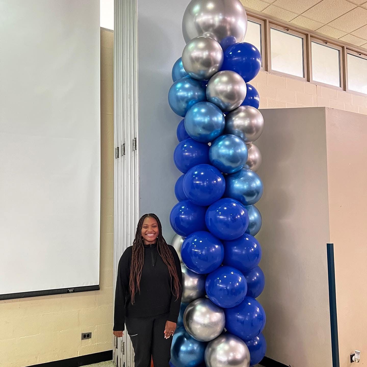 20-foot grand spiral balloon column in blue, chrome blue, and chrome silver, creating a bold and eye-catching statement for a presentation or event stage backdrop.