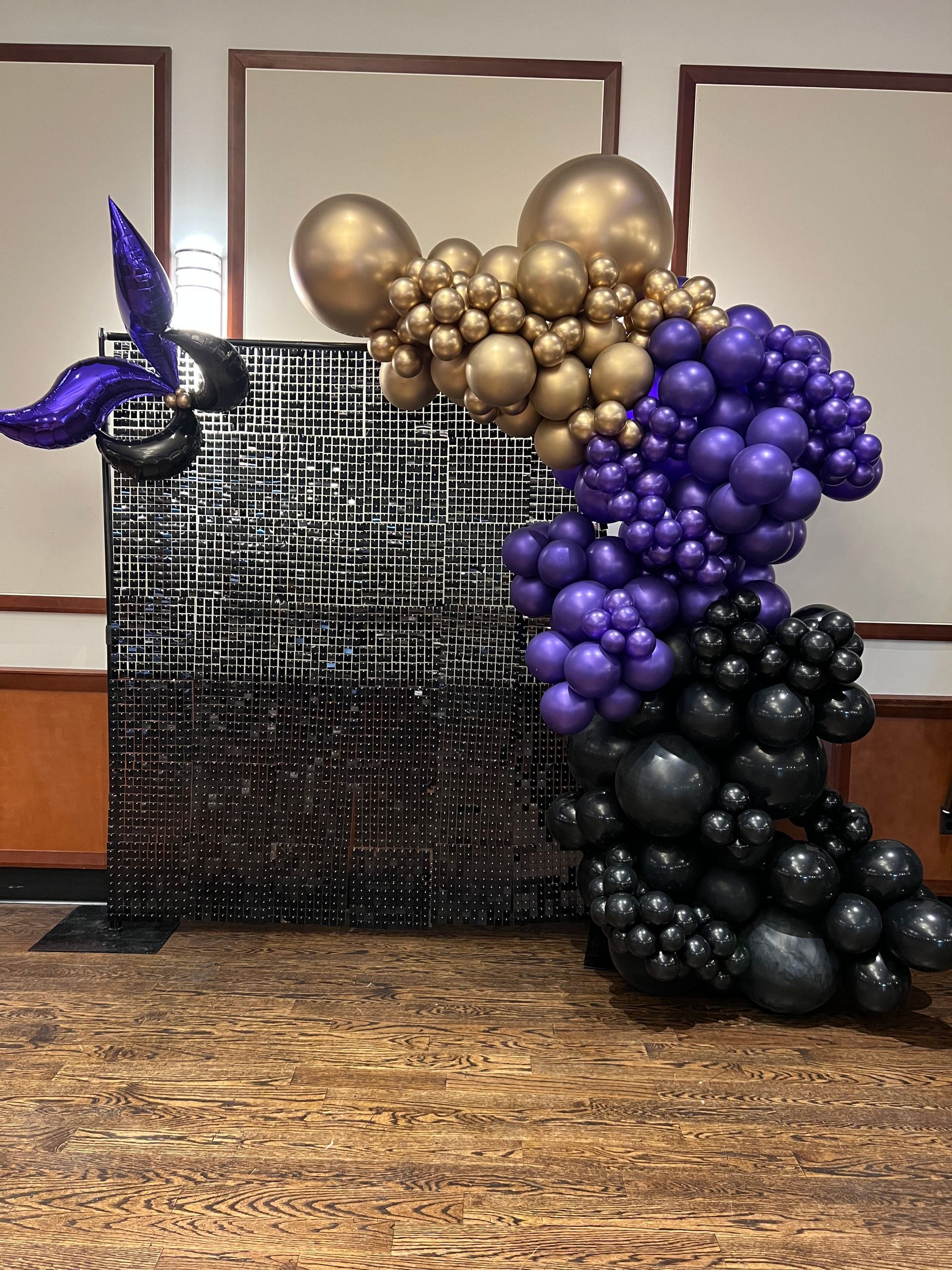 black shimmer wall and a deluxe balloon garland for a mardi gras themed balloon demi arch garland 
