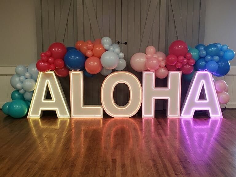 Aloha LED marquee display for a corporate event, enhanced with a vibrant balloon garland, perfect for tropical-themed events, and eye-catching decor.