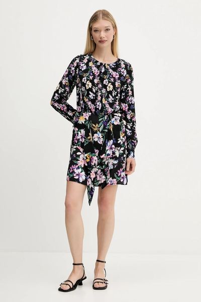 Donna con abito floreale nero, appoggiata e con sandali, su sfondo bianco.
