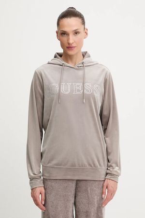 Donna in piedi in un ambiente interno, con indosso una felpa grigia Guess con logo e coulisse.