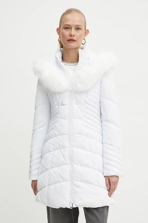 Donna in piumino bianco con collo di pelliccia, in piedi, che guarda avanti.