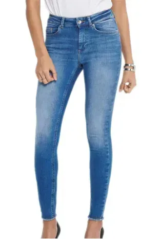 Donna in jeans attillati blu e top bianco, mani lungo i fianchi.