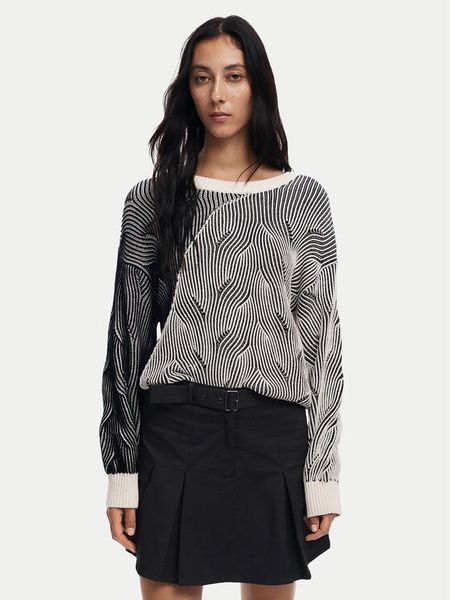 Donna che indossa un maglione fantasia e una gonna nera, in posa, con lo sguardo rivolto al futuro.