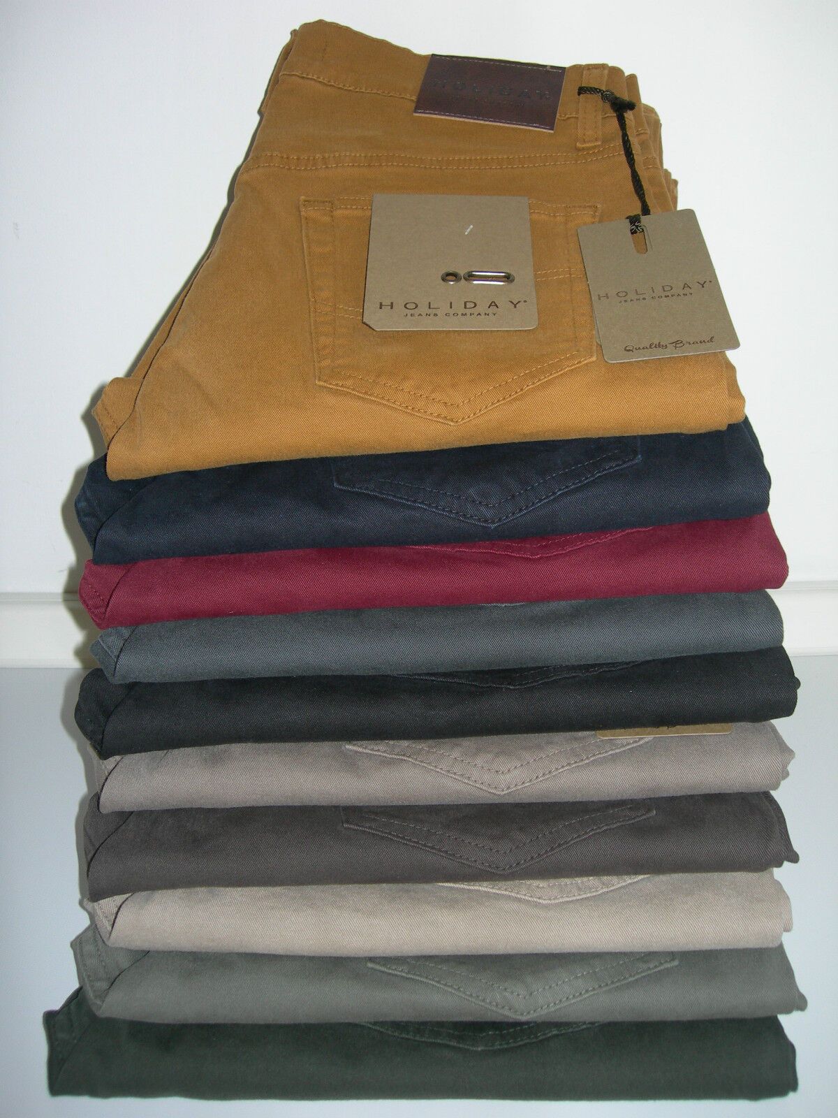 Pila di pantaloni di velluto a coste piegati in vari colori con etichette attaccate.