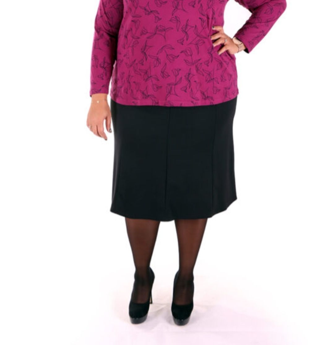 Donna con top magenta e gonna nera, mano sul fianco, tacchi neri.