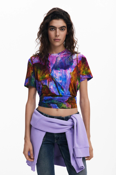 Donna con top colorato e jeans, che indossa un maglione viola legato in vita.