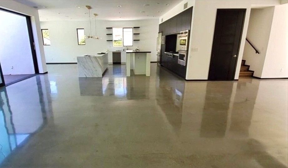 A large room with a shiny concrete floor and a kitchen.