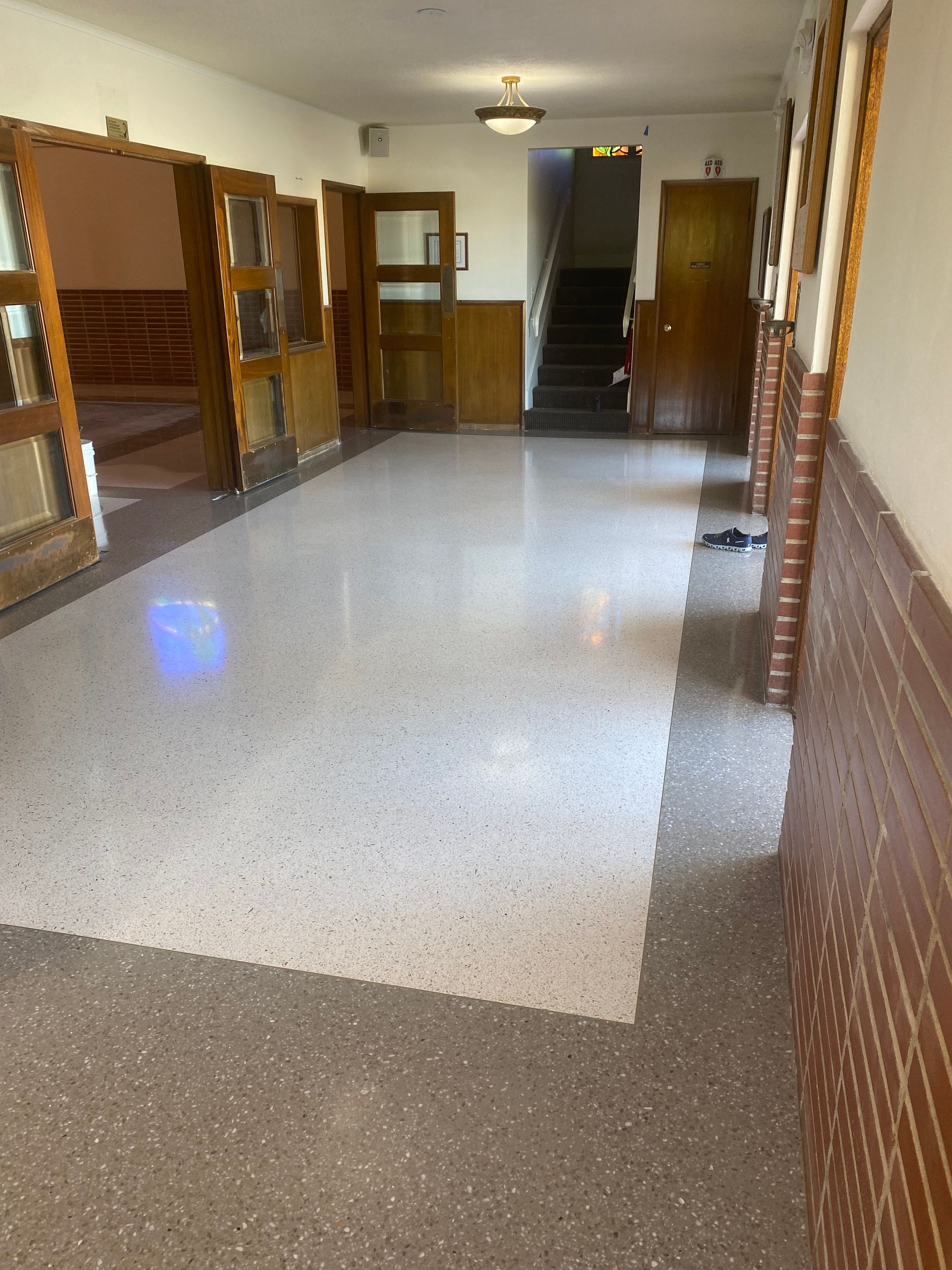 A long hallway with a staircase leading up to the second floor of a building.