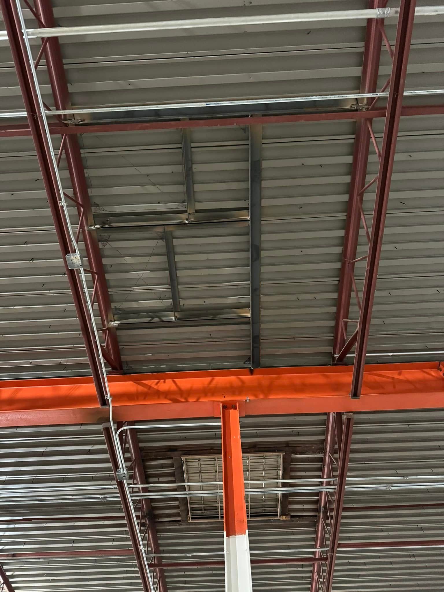 Red metal structure with corrugated roof, some wood damage visible from below.