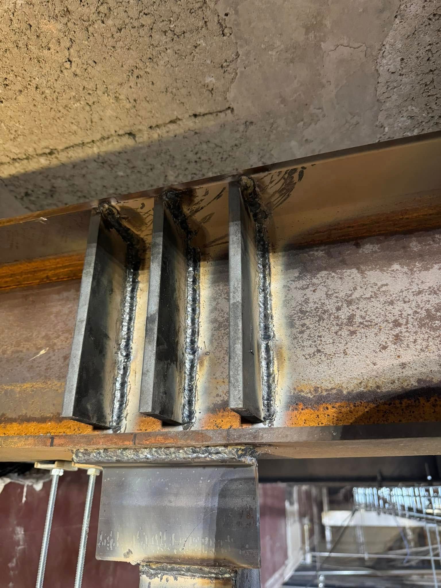 Steel beams with welded supports, industrial setting.