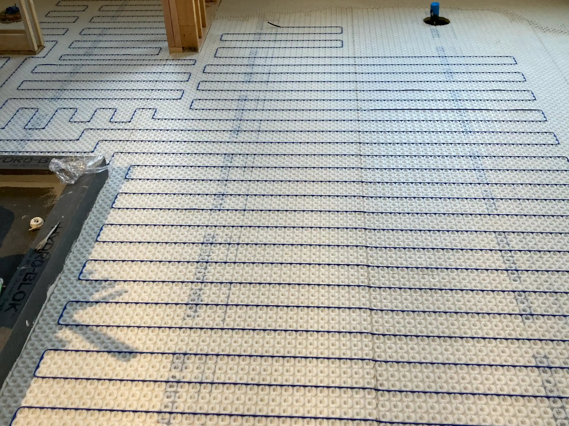 Coiled tubing laid in neat rows on a floor, with wooden supports and a small blue tool in the background