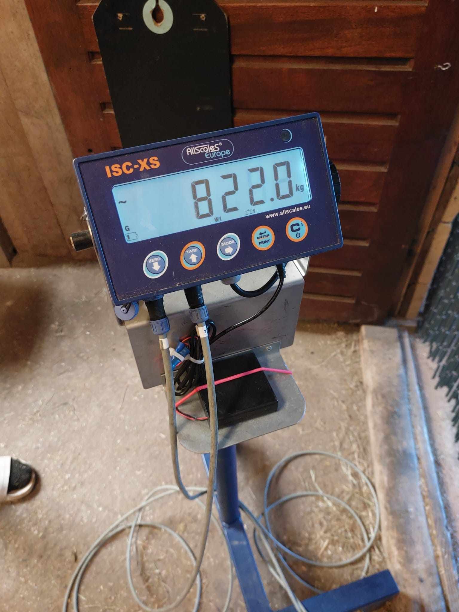 Blauw elektronisch display op een standaard met de aanduiding 8220.0, met kabels in een deuropening van een werkplaats.