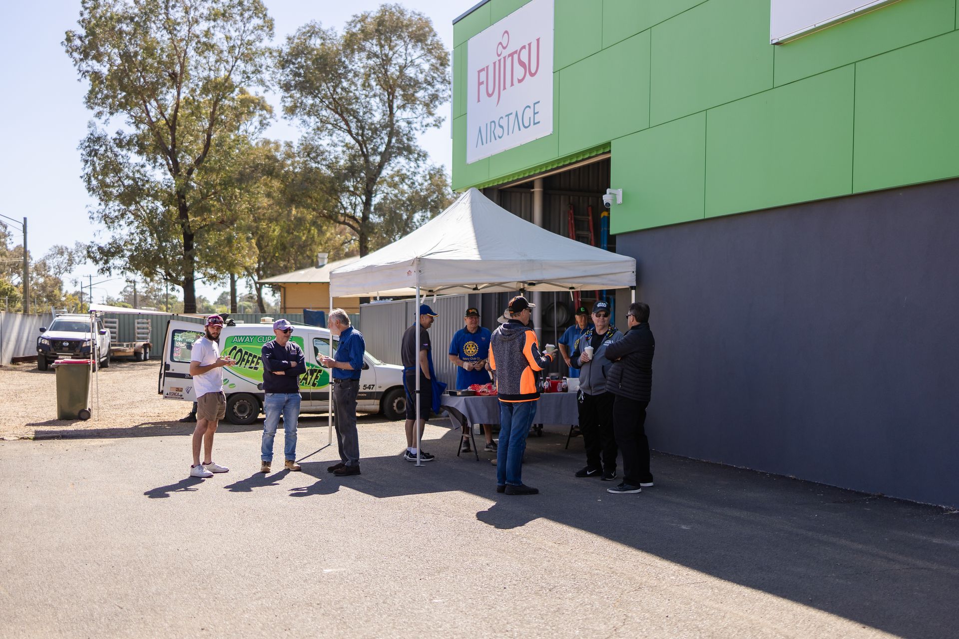 A group of people are standing in front of a MedleyRefrigeration and Air Conditioning building.