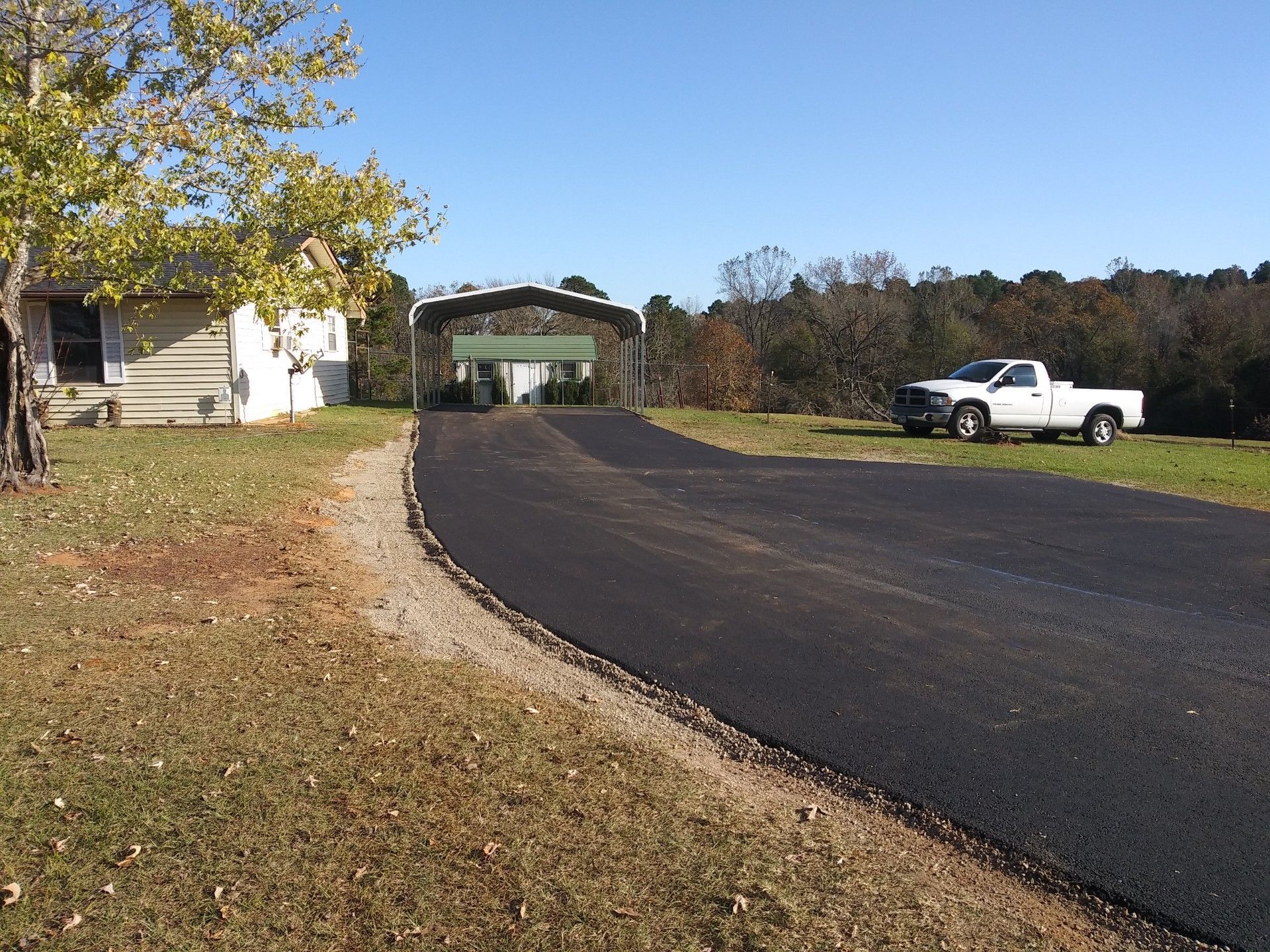 A white truck is parked on the side of a road next to a house.