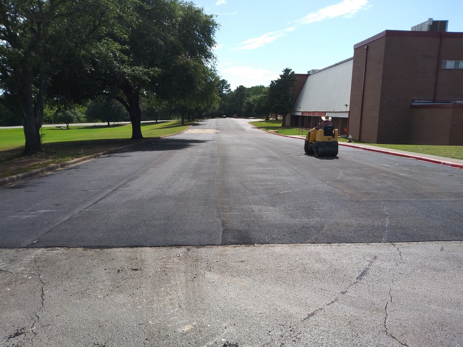 A yellow vehicle is driving down a road in front of a building