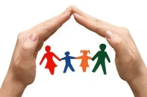 Hands sheltering a paper cutout family, symbolizing protection.