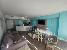 Open-concept living space with a kitchen, dining area, and living room in a coastal-themed apartment.