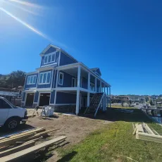 Blue house under construction near water on a sunny day.