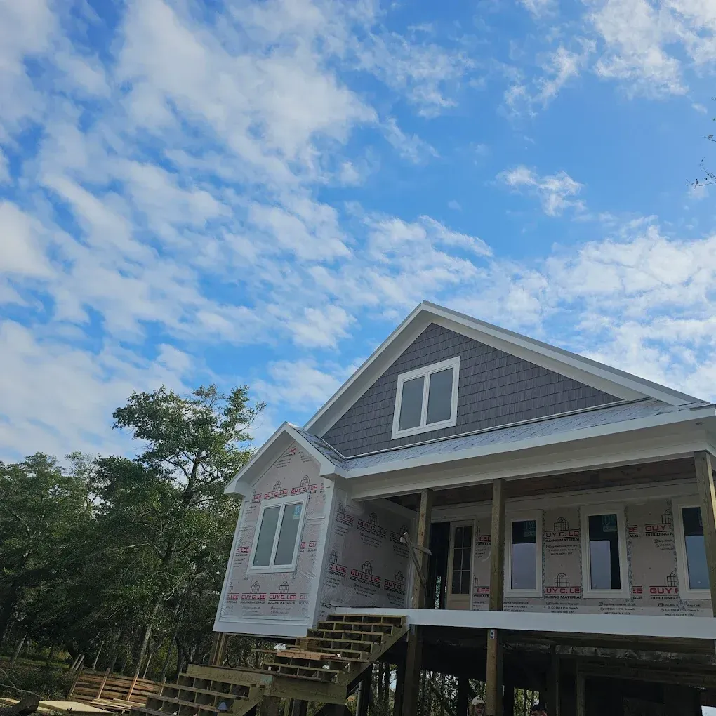 House under construction with blue sky and clouds.
