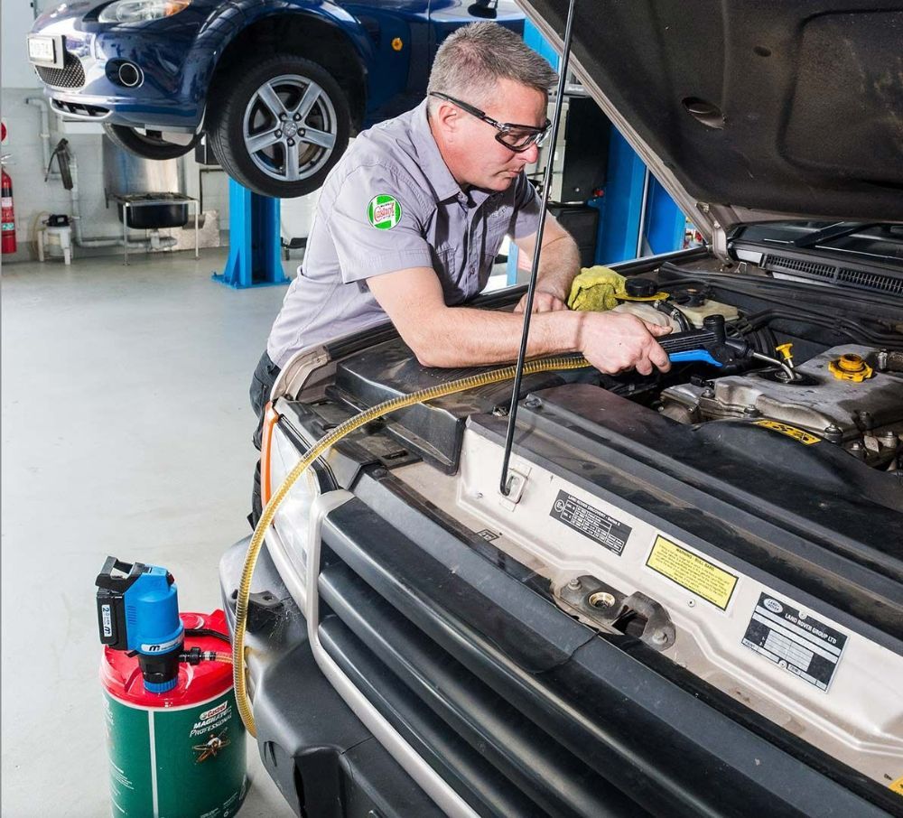A Man Is Working Under the Hood of A Car — Wades Distributors In Mackay, QLD