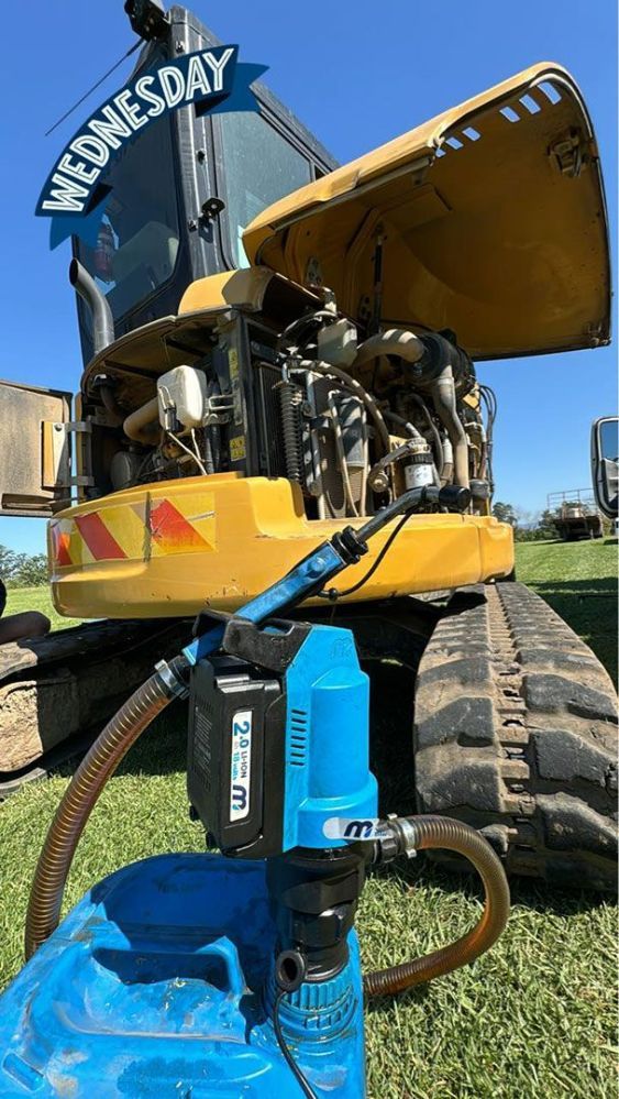 A Yellow Tractor with Its Hood up Is Being Fueled by A Blue Tank — Wades Distributors In Townsville, QLD