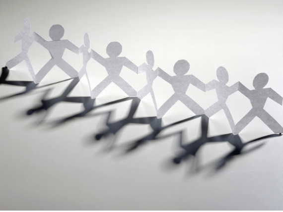 Paper chain of gray human figures casting shadows on a white background