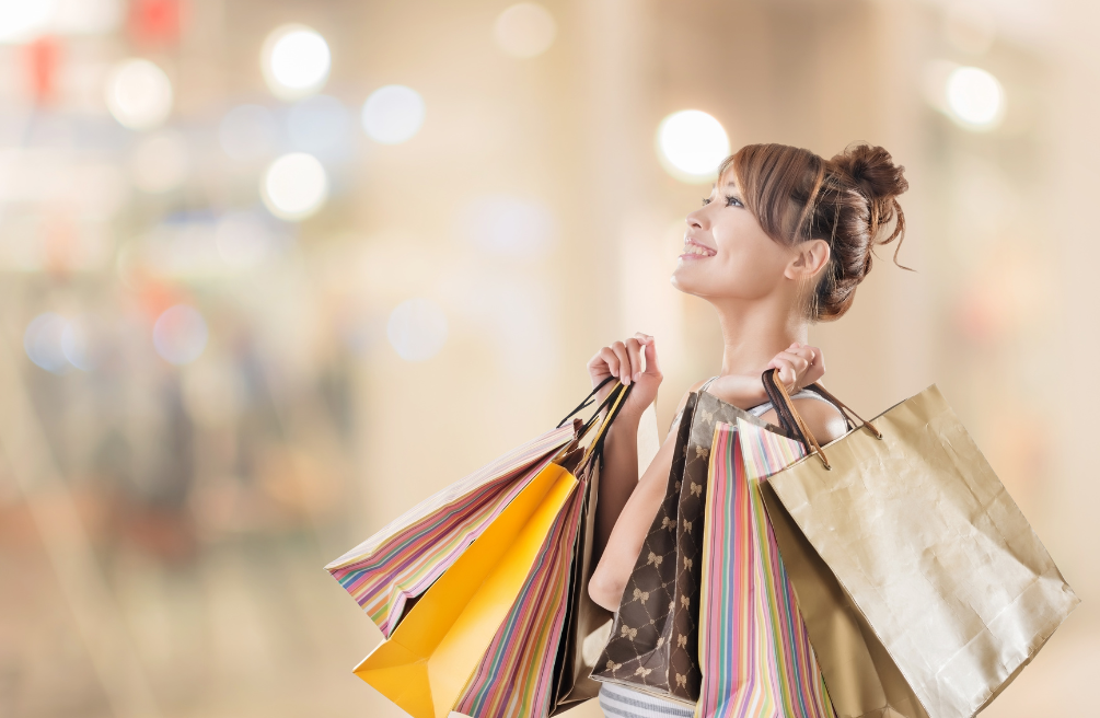 Smiling shopper holding colorful shopping bags in a bright mall