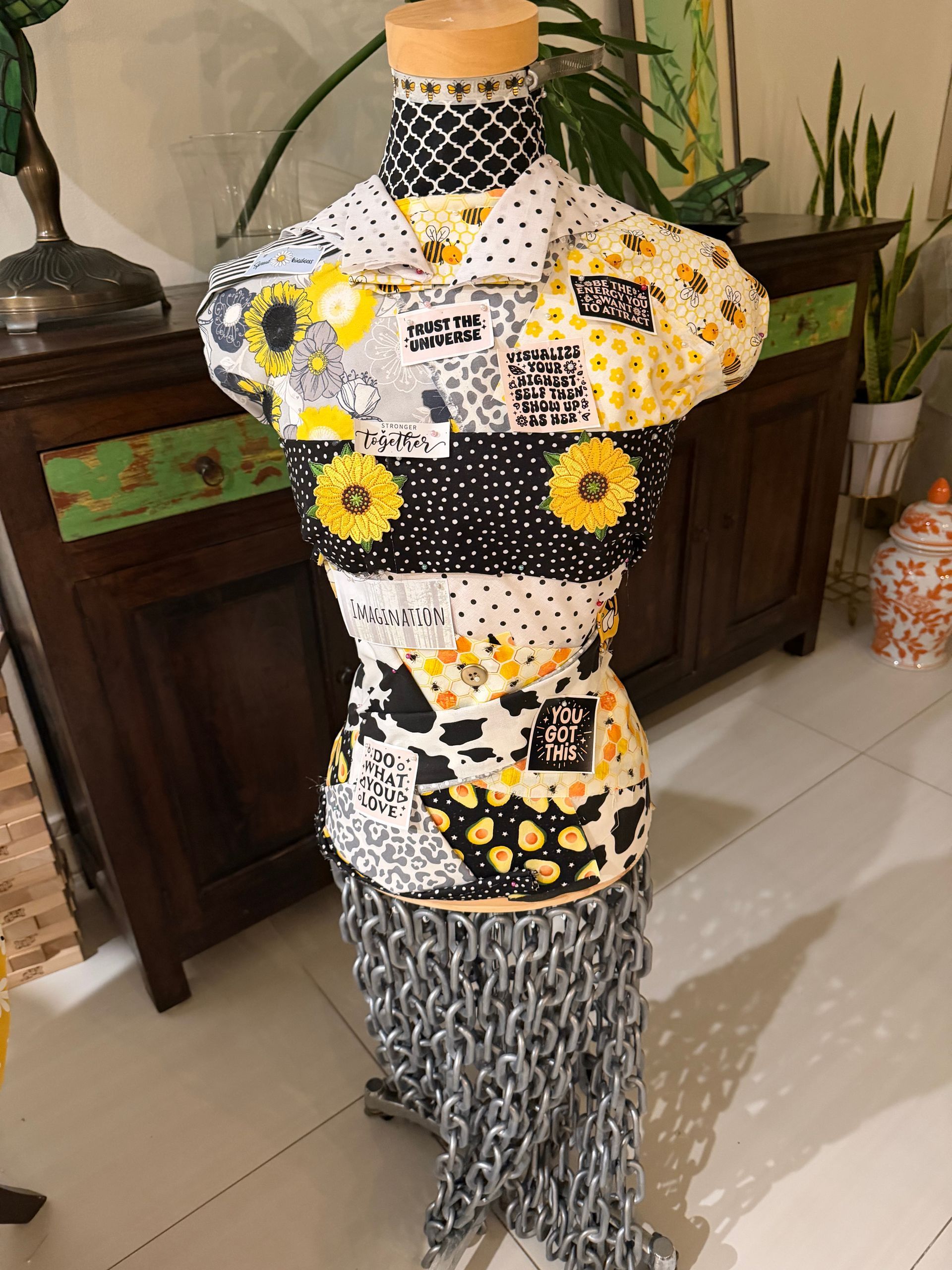 Mannequin wearing a black, white, and yellow patterned dress in a home interior.