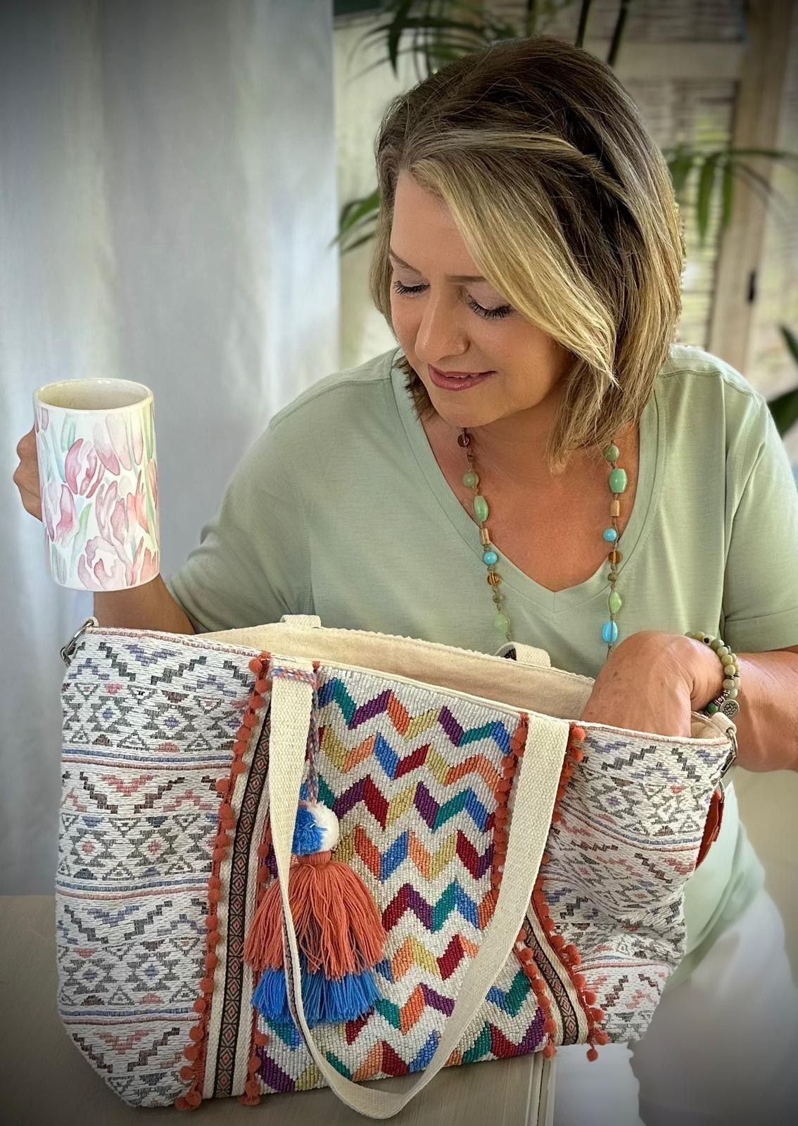 Woman looking into a patterned woven bag beside a mug on a table