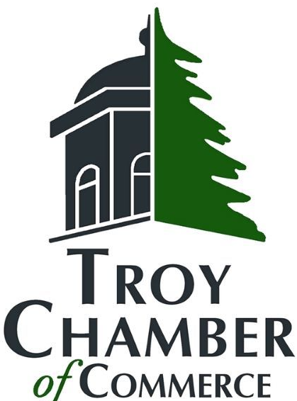 the troy chamber of commerce logo has a building and a tree on it .