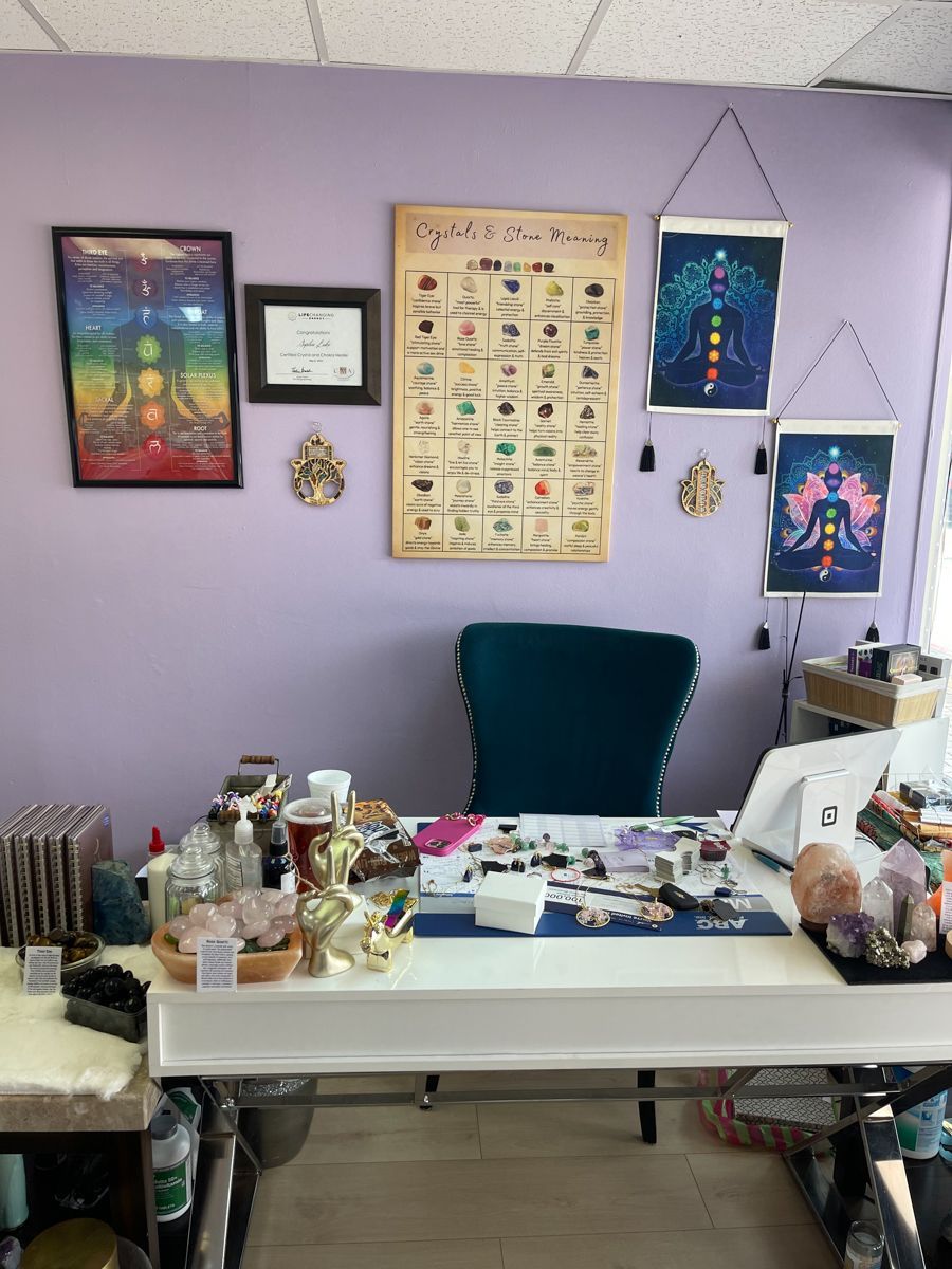 A desk with crystals, art, and a chair against a lavender wall; likely a healing or spiritual space.