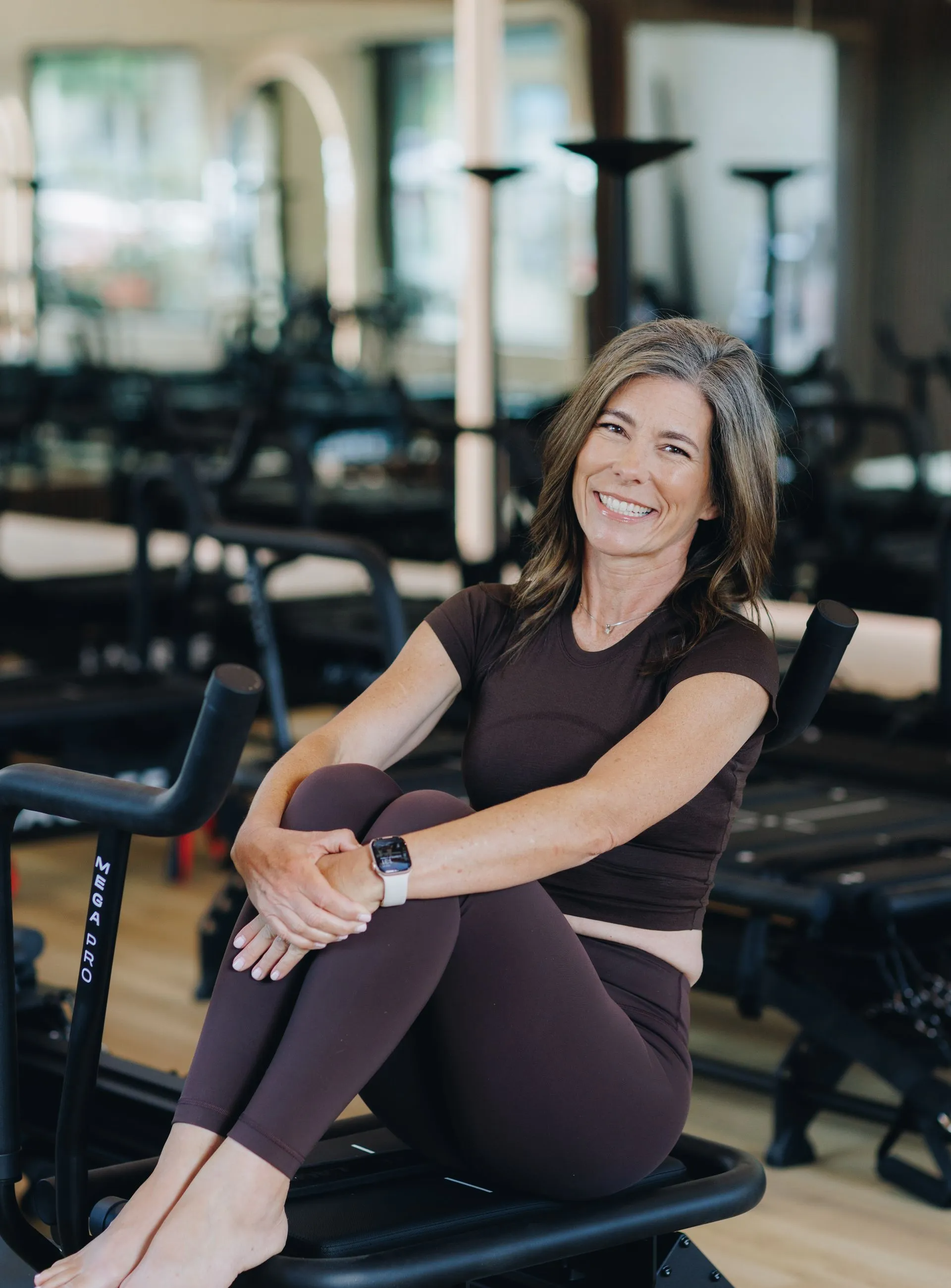 Woman smiling while seated on gym equipment in a fitness studio