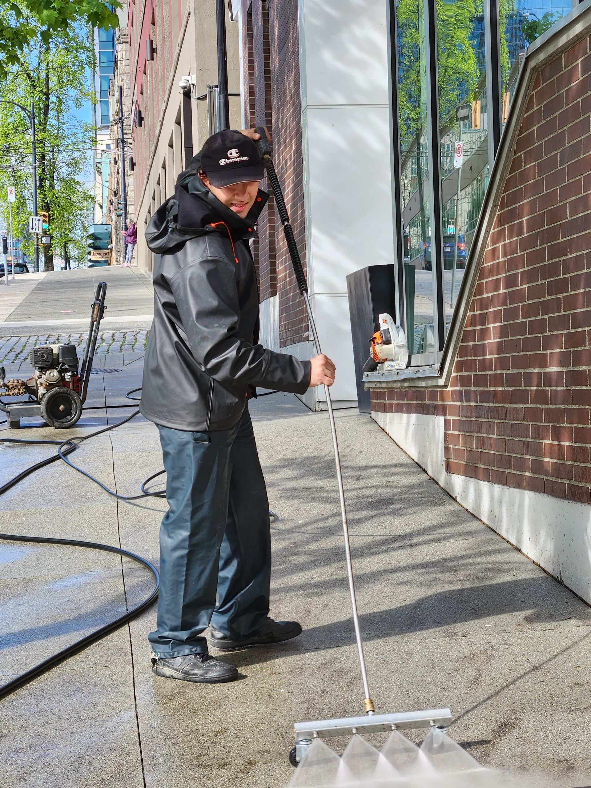 A man is cleaning a sidewalk with a high pressure washer.