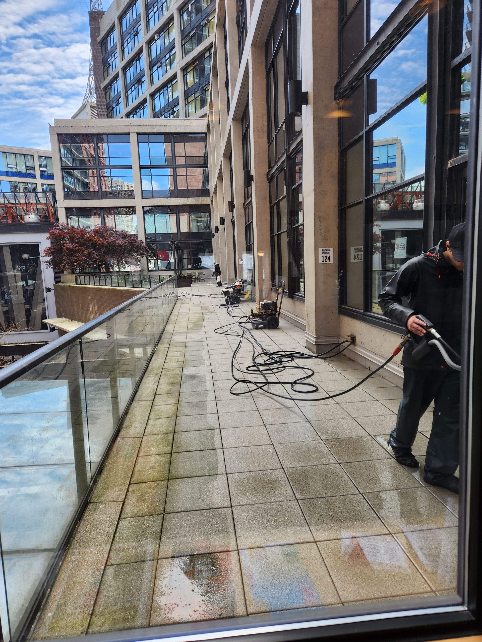 A man is cleaning the sidewalk outside of a building.