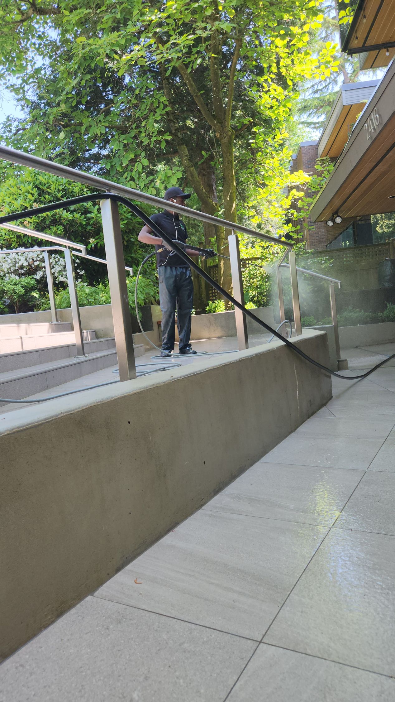 A man is cleaning a balcony with a high pressure washer.