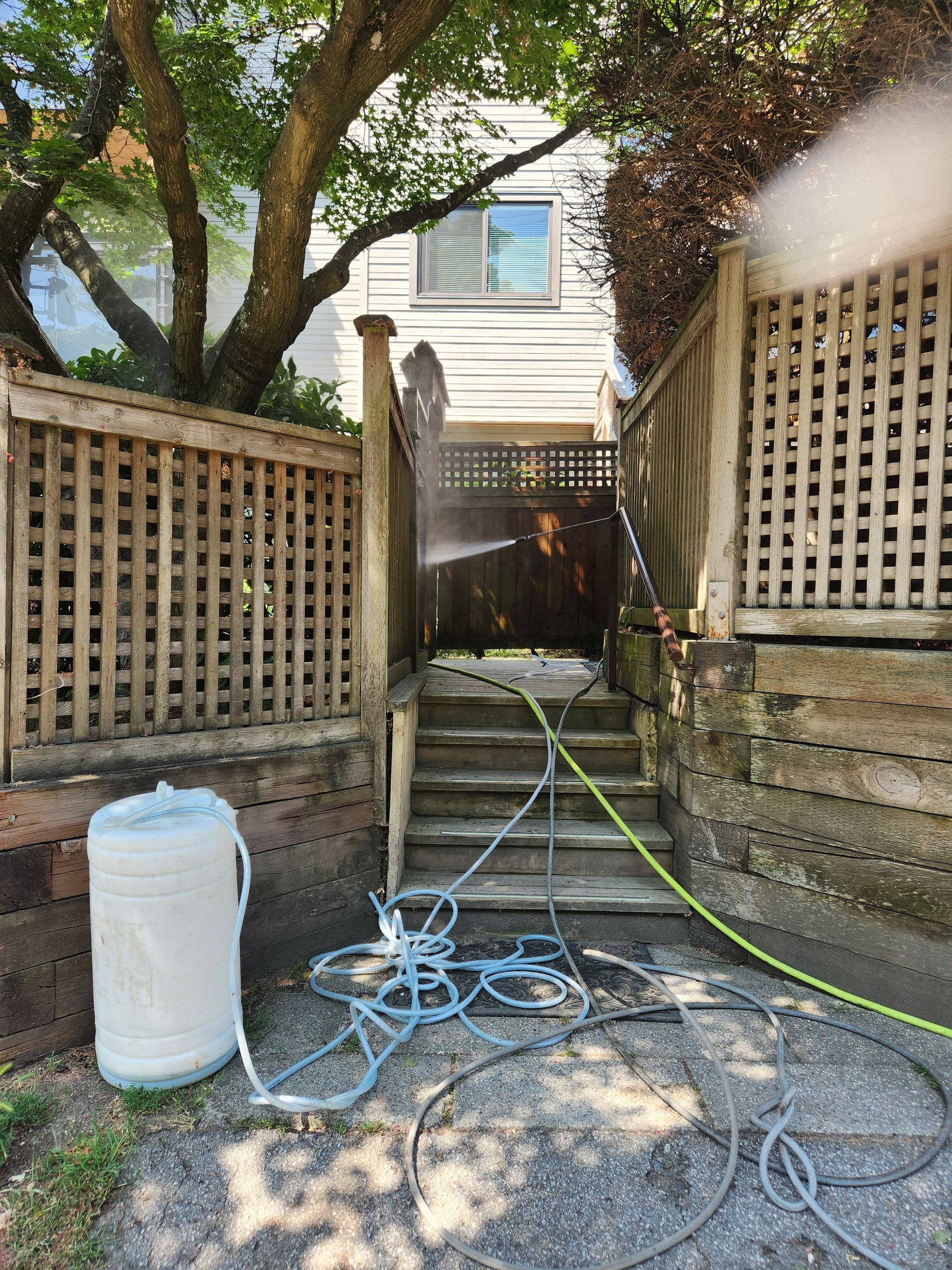 A man is cleaning the stairs of a house with a pressure washer.