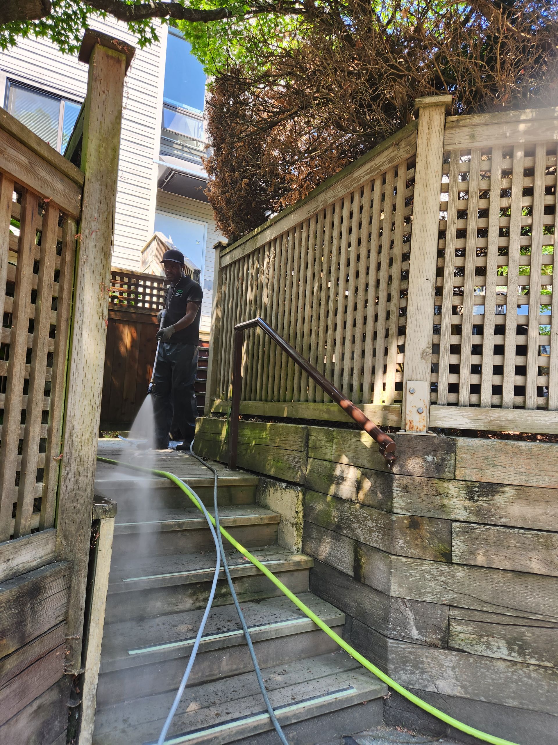A man is cleaning the stairs of a house with a pressure washer.