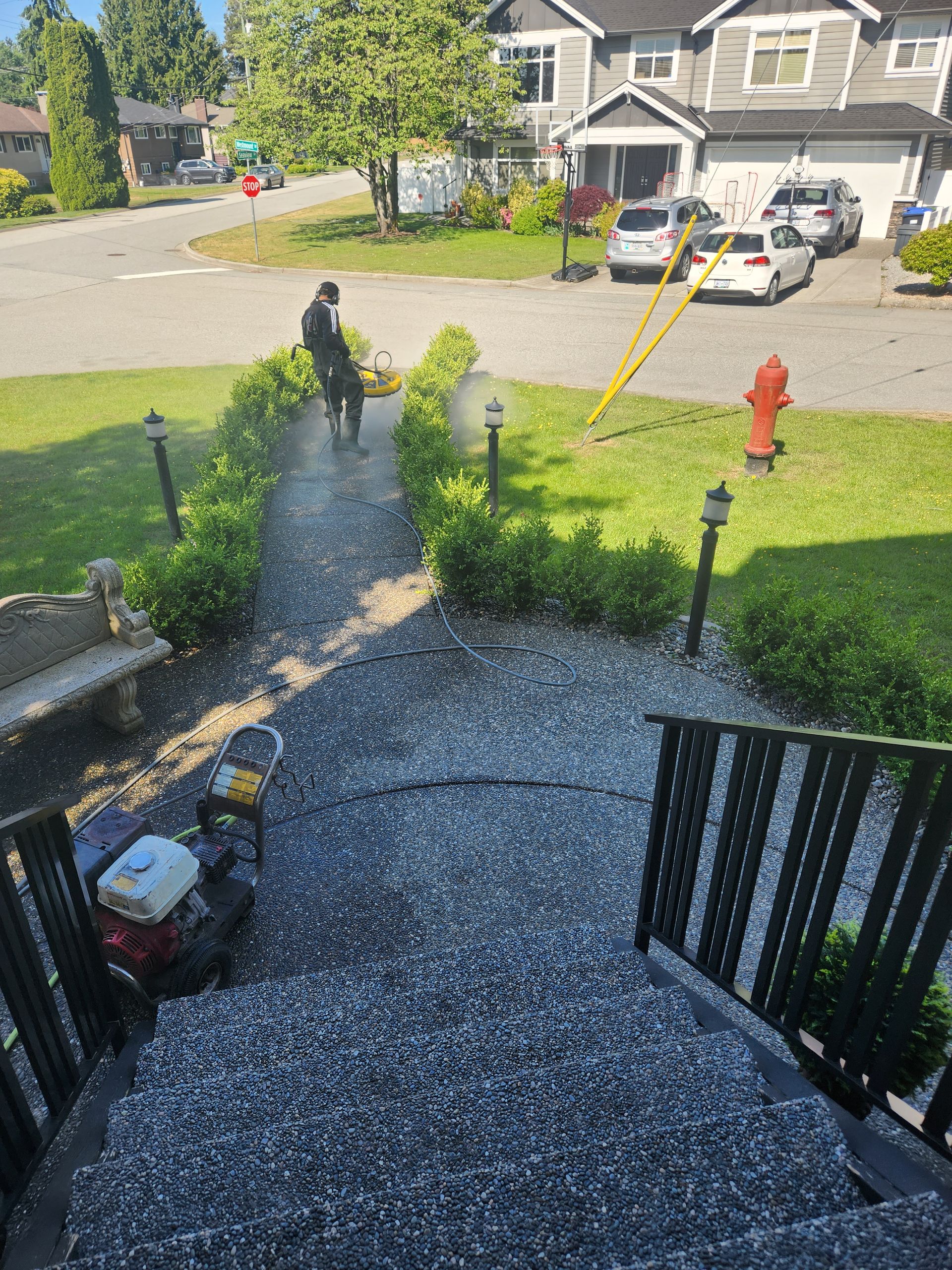 A man is cleaning a sidewalk next to a fire hydrant.